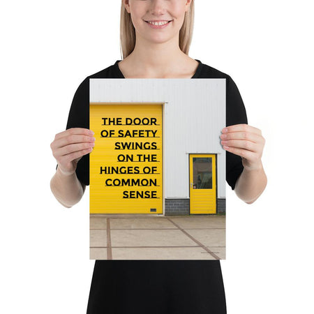 Workplace safety poster depicting a bright yellow garage door to a warehouse with a bold safety slogan on it with a smaller yellow door to the right.