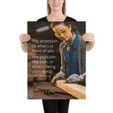 Workplace safety poster of a young female woodworker wearing safety glasses and gloves and sanding a two by four in her shop with a safety quote to the left.
