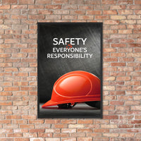 A workplace safety poster showing a red hard hat in front of a grey, industrial-looking background with the slogan safety is everyone's responsibility.