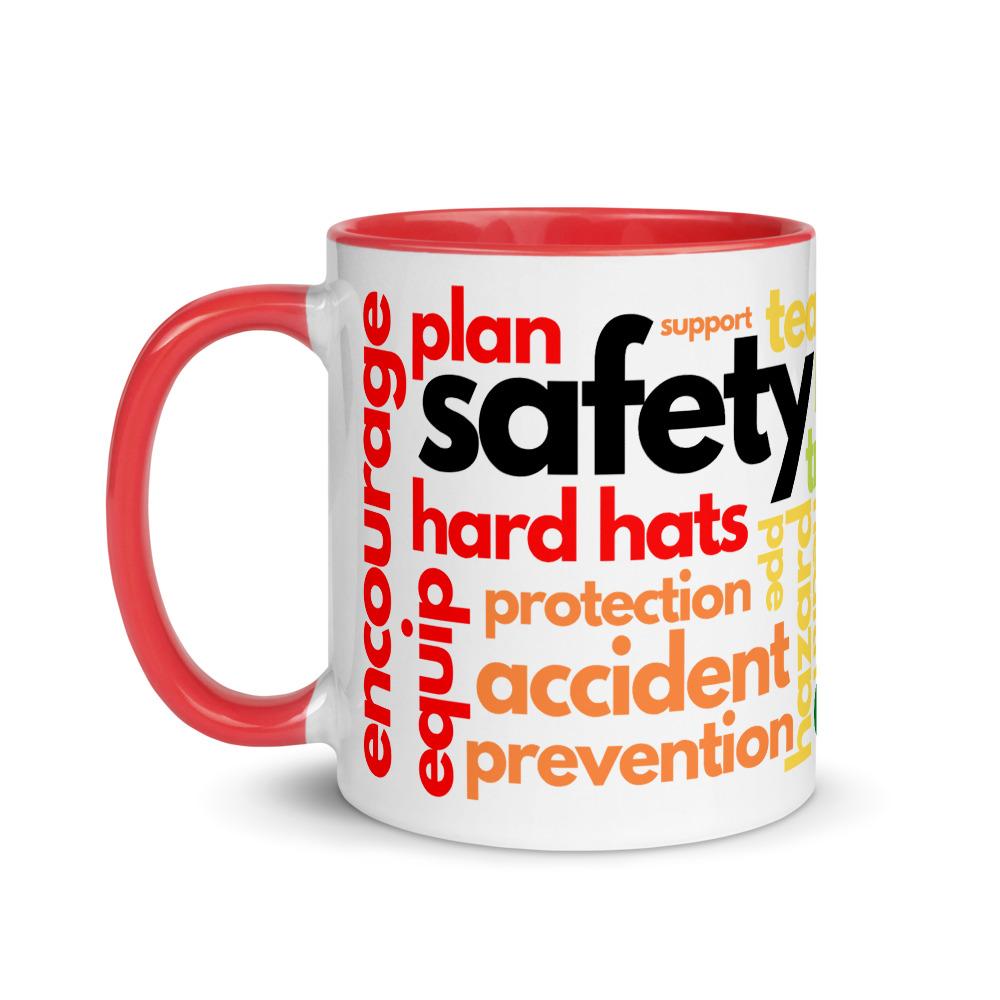 White ceramic mug with safety terms like hard hats, protection, and encourage, in a rainbow pattern across the mug with a red rim, inside, and handle.