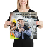 A workplace safety poster showing two workers in hardhats, reflective vests, and safety glasses collaborating together in a factory with the quote no one is wise enough by themselves by Plautus.