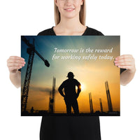A safety poster showing a worker on a construction site being silhouetted by a sunset of orange and blue colors with the slogan tomorrow is the reward for working safely today.