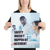 Male and female workers wearing lab coats and safety glasses while inspecting a test tube with a safety slogan written in bold text.