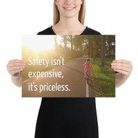 A safety poster showing a little girl riding her bike down a road on a sunny day with the slogan safety isn't expensive, it's priceless.