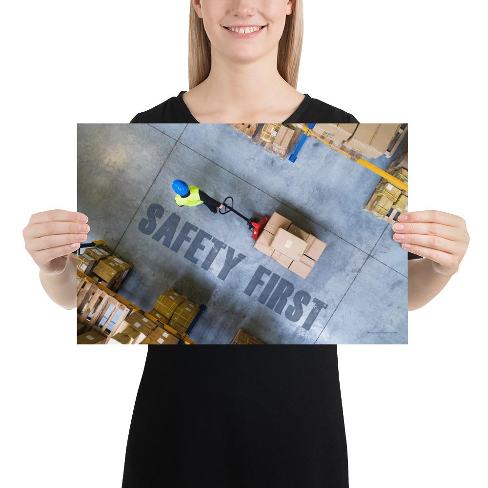 A safety poster showing a bird's-eye view of a worker in a warehouse pulling boxes on a pallet jack with the slogan safety first in bold letters.