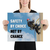 A fully harnessed man wearing a hard hat scaling the side of a building with a bright blue sky and clouds in the background with the text safety by choice, not by chance in bold text to his left.