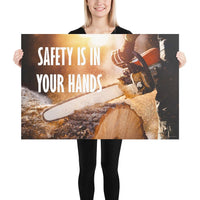 A safety poster showing a close-up of a man's hands holding a chainsaw sawing through a log with sawdust flying everywhere with the text safety is in your hands to the left.