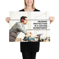 A workplace safety poster of a man in safety glasses and earmuffs taking a break in his woodshop with a safety slogan to the right.