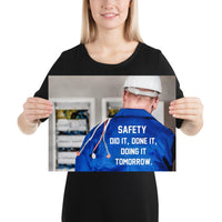 Safety poster showing an electrician wearing a hard hat and holding cables working on an electrical panel with text on the back of his bright blue shirt.