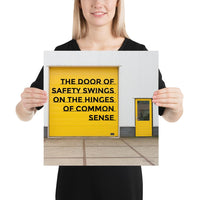 Workplace safety poster depicting a bright yellow garage door to a warehouse with a bold safety slogan on it with a smaller yellow door to the right.
