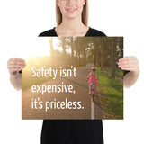 A safety poster showing a little girl riding her bike down a road on a sunny day with the slogan safety isn't expensive, it's priceless.
