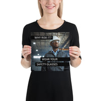 An eye safety poster showing a man in a white hard hat and safety glasses in a warehouse with the slogan "Why risk it? Wear your safety glasses."