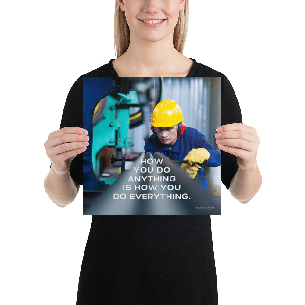 A safety poster showing a man in a yellow hard hat, red earmuffs and safety glasses, working in a factory with the slogan "How you do anything is how you do everything" below him.