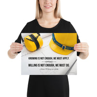A safety poster showing a yellow hard hat and yellow ear muffs on blueprints with a safety quote by Johann Wolfgang von Goethe that says "Knowing is not enough, we must apply. Willing is not enough, we must do."
