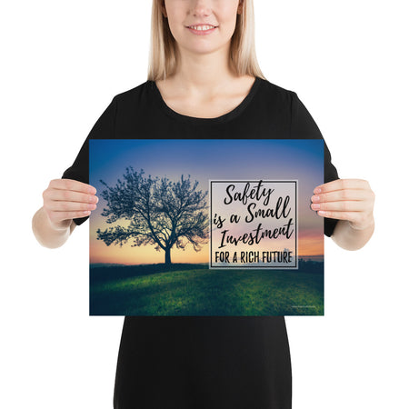 A workplace safety poster showing a lush green field at dusk with the silhouette of a huge tree and the slogan "Safety is a small investment for a rich future."