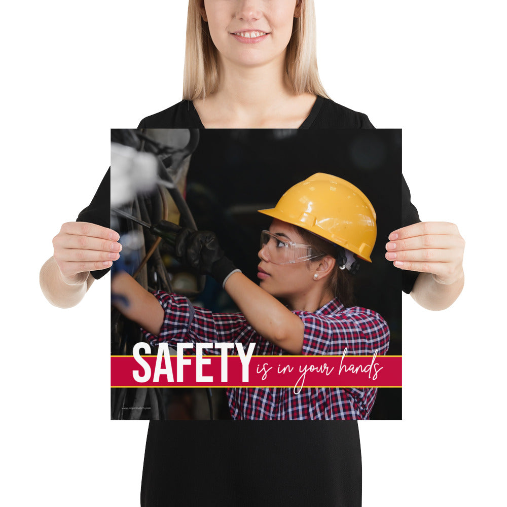 A construction safety poster depicting a woman in a hard hat, gloves, and safety glasses working with the slogan "Safety is in your hands."