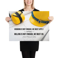 A safety poster showing a yellow hard hat and yellow ear muffs on blueprints with a safety quote by Johann Wolfgang von Goethe that says "Knowing is not enough, we must apply. Willing is not enough, we must do."