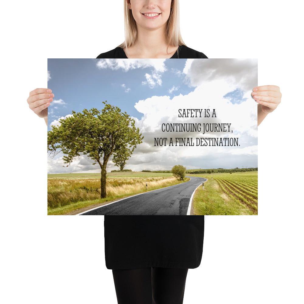 A workplace safety poster depicting a beautiful sunny day with a bright blue sky and a lush green field being cut down the middle by a road leading off into the countryside with the text safety is a continuing journey, not a final destination.