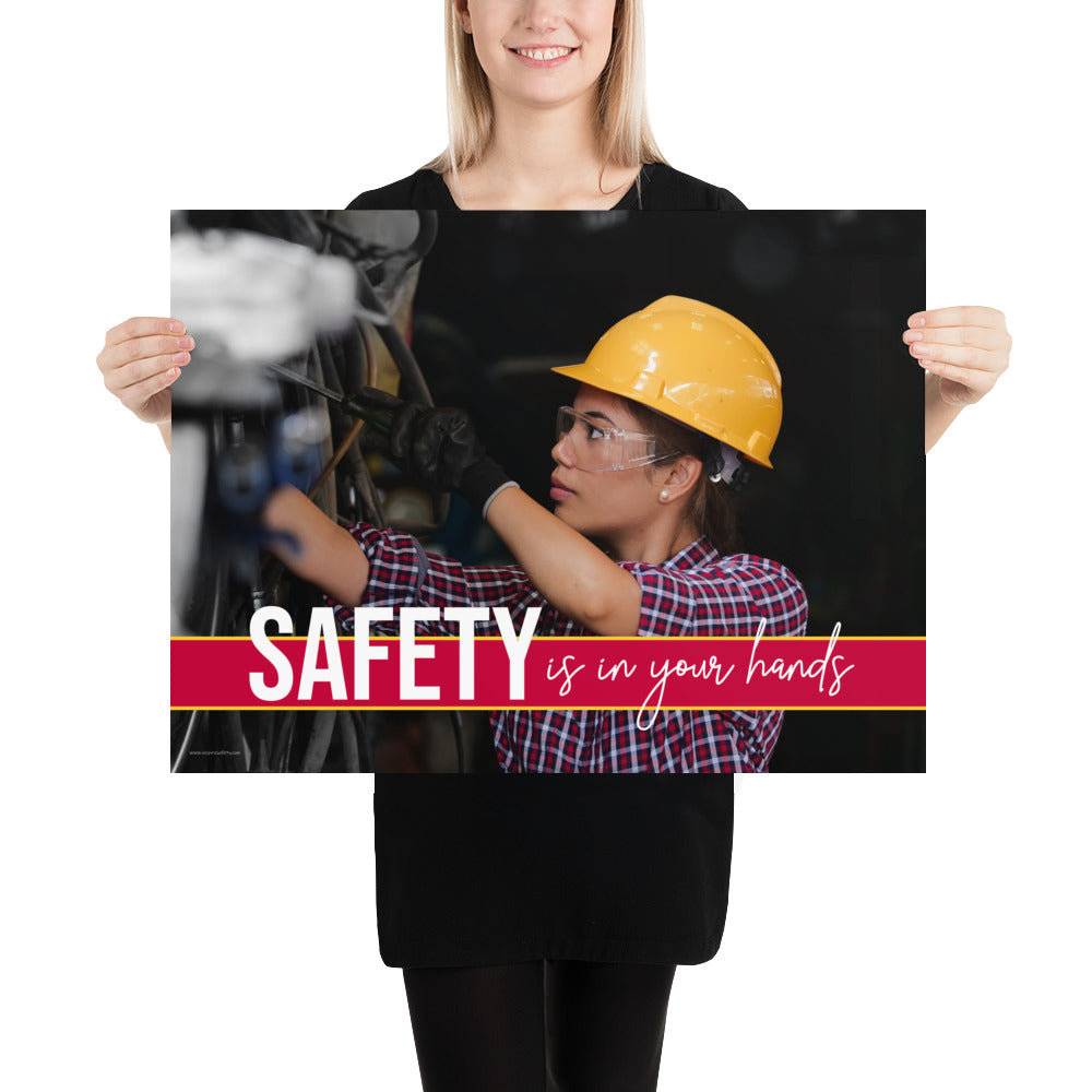 A construction safety poster depicting a woman in a hard hat, gloves, and safety glasses working with the slogan "Safety is in your hands."