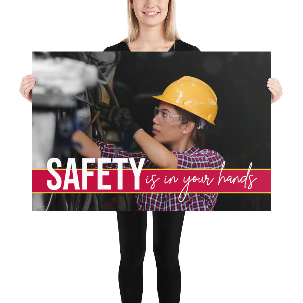 A construction safety poster depicting a woman in a hard hat, gloves, and safety glasses working with the slogan "Safety is in your hands."