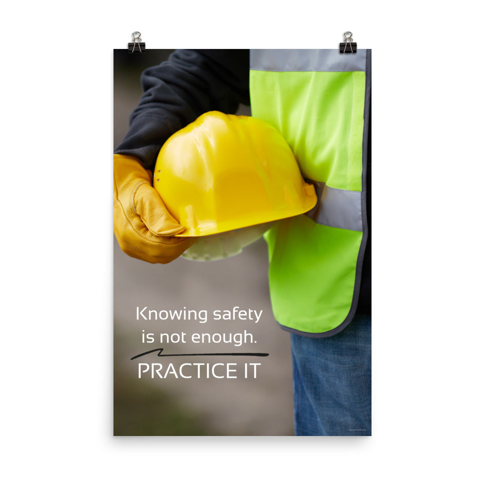 A safety poster showing a construction worker in a reflective vest and gloves holding a hard hat with the slogan "Knowing safety is not enough. Practice it."