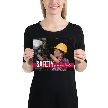 A construction safety poster depicting a woman in a hard hat, gloves, and safety glasses working with the slogan "Safety is in your hands."