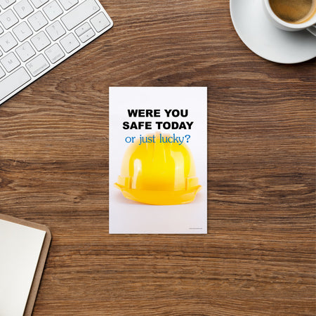 A workplace safety mini poster showing a yellow hard hat on a plain white background with the slogan were you safe today, or just lucky?