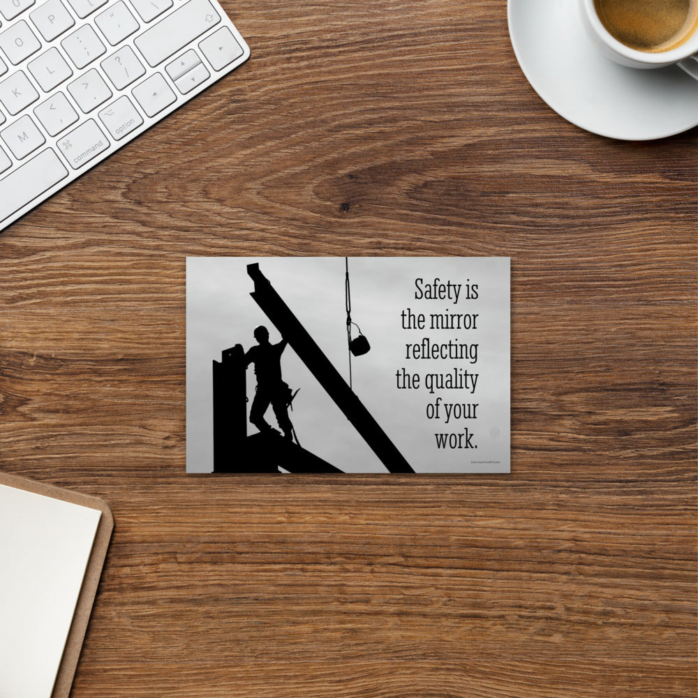 A workplace safety print showing a construction ironworker working on a construction site with everything silhouetted black with a light grey background and with the slogan safety is the mirror reflecting the quality of your work.
