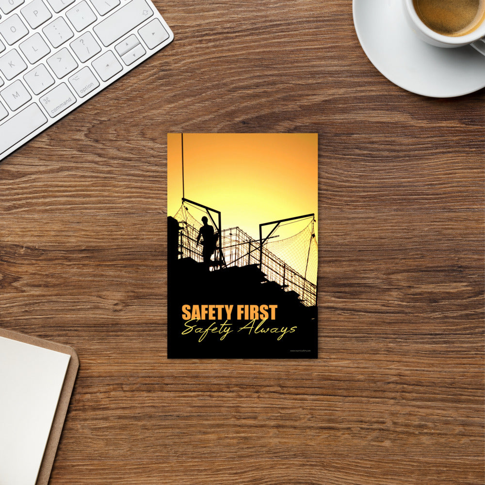 A workplace safety print showing a construction site and construction workers being silhouetted by a bright and beautiful sunset of different shades of orange with the slogan safety first, safety always.