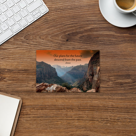 A safety print showing a landscape of burnt orange tinted mountains with the sunlight piercing through the tops of the mountains with the quote our plans for the future descend from the past by Seneca.