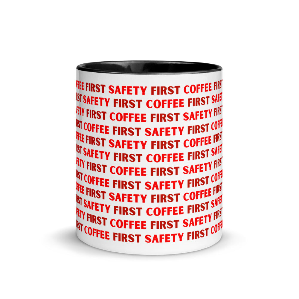 White ceramic mug with red repeating text that says "Safety First, Coffee First" with a black rim, inside, and handle.
