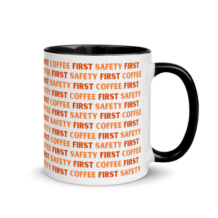 White ceramic mug with orange repeating text that says "Safety First, Coffee First" with a black rim, inside, and handle.