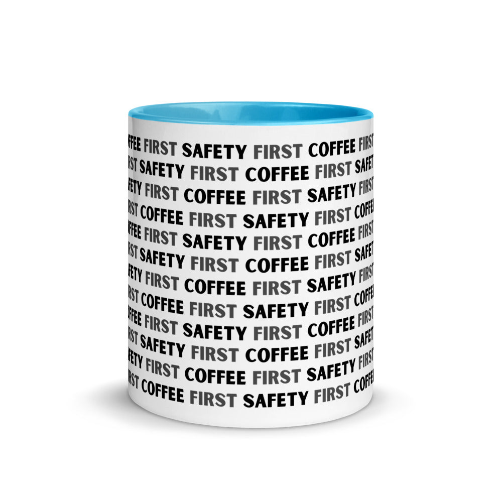 White ceramic mug with black repeating text that says "Safety First, Coffee First" with a blue rim, inside, and handle.