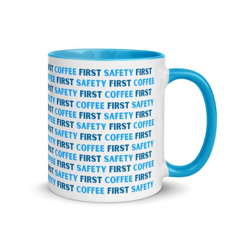 White ceramic mug with blue repeating text that says "Safety First, Coffee First" with a blue rim, inside, and handle.