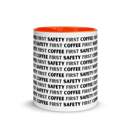 White ceramic mug with black repeating text that says "Safety First, Coffee First" with a orange rim, inside, and handle.