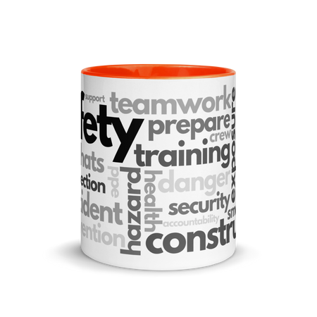 White ceramic mug with safety terms like hard hats, protection, and encourage, in a various shades of black and grey across the mug with an orange rim, inside, and handle.