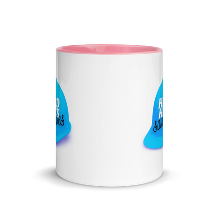 White ceramic mug with a blue hard hat with text that says "Hard hats save lives" with a pink rim, inside, and handle.