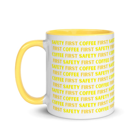 White ceramic mug with yellow repeating text that says "Safety First, Coffee First" with a yellow rim, inside, and handle.