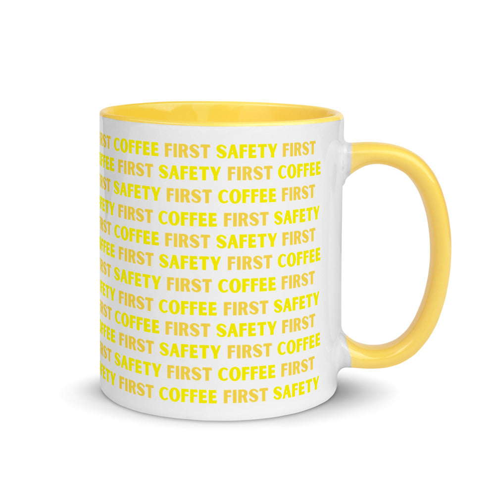 White ceramic mug with yellow repeating text that says "Safety First, Coffee First" with a yellow rim, inside, and handle.